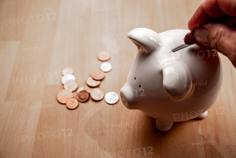 Male hand puts cent coin in piggy bank