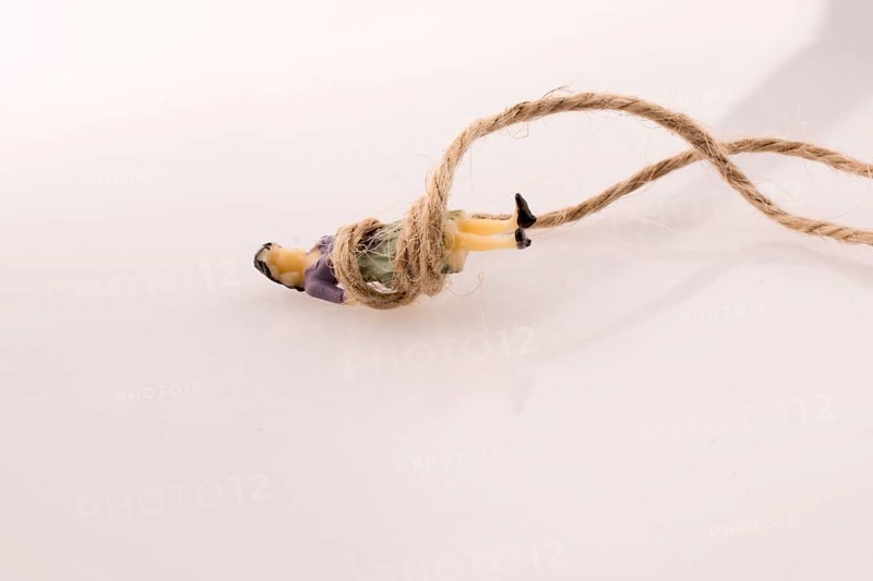 Woman figure lying down tied with a linen thread on a white background