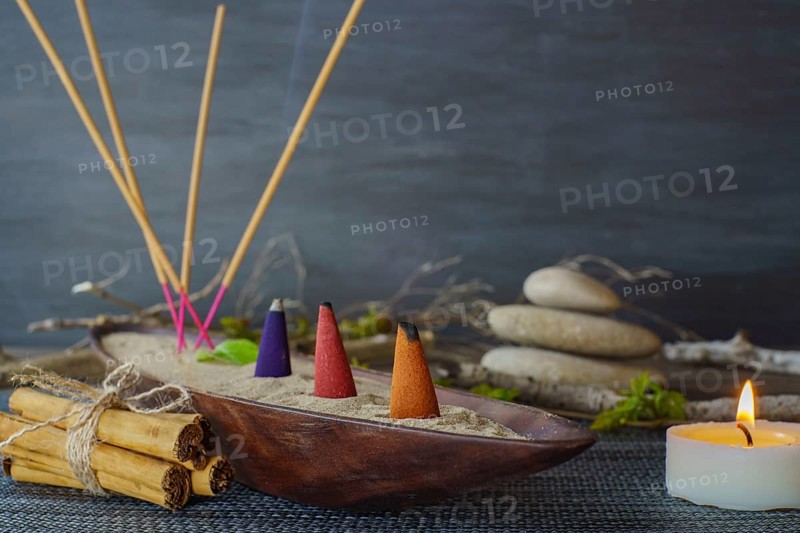 Various types of incense smoking in a wooden bowl with sand