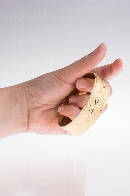 Hand with a golden bracelet on a white background
