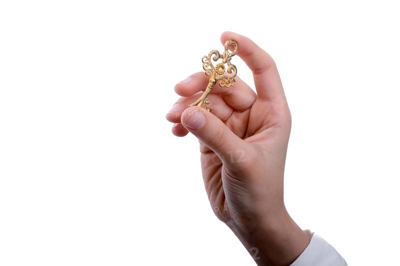 Hand holding a retro styled metal key on a white background