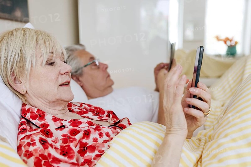 Elderly couple lying in bed together in their bedroom