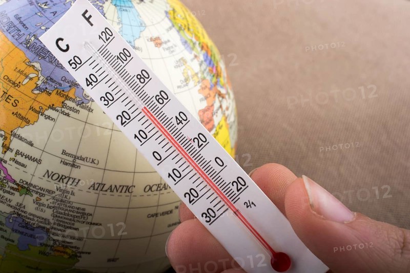 Hand placing a thermometer on a little model globe