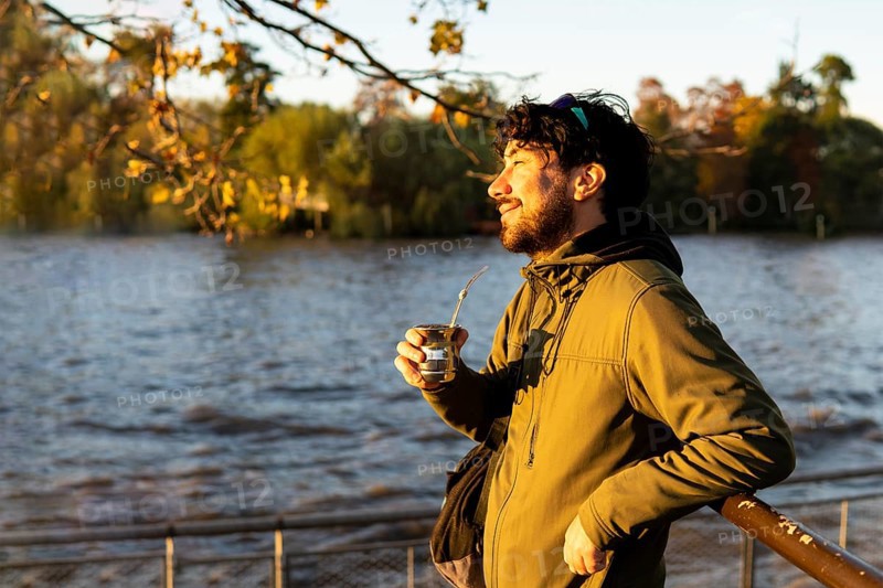 Latin man enjoying the sunset at the river while drinking mate