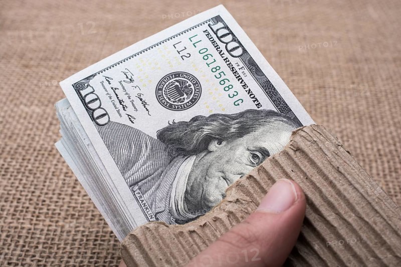 Hand holding banknote bundle of US dollar on a linen canvas background