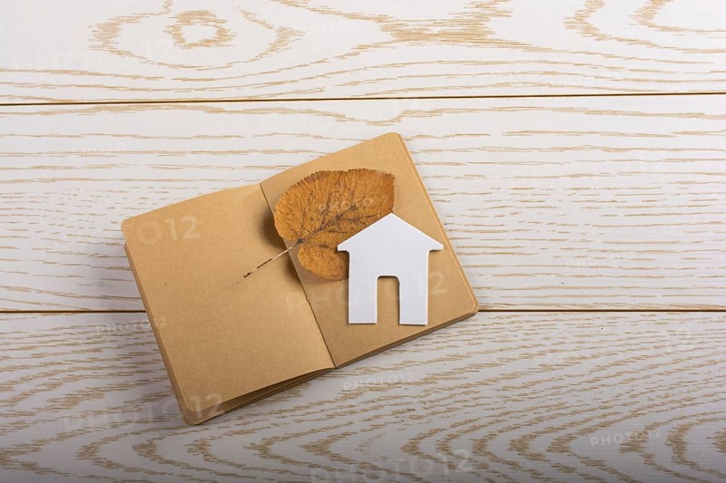 Little paper house on a notebook on parquet