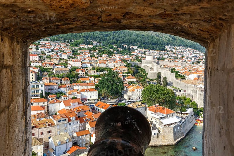 View of the old town through an opening in the wall of the fortress with a cannon in Dubrovnik