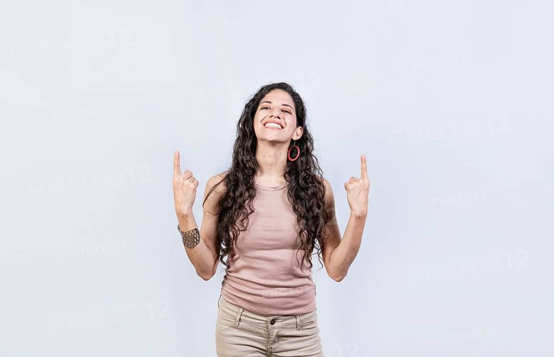 Young girl pointing an advertisement with fingers up. Smiling woman pointing with both fingers up isolated. People recommending with fingers up