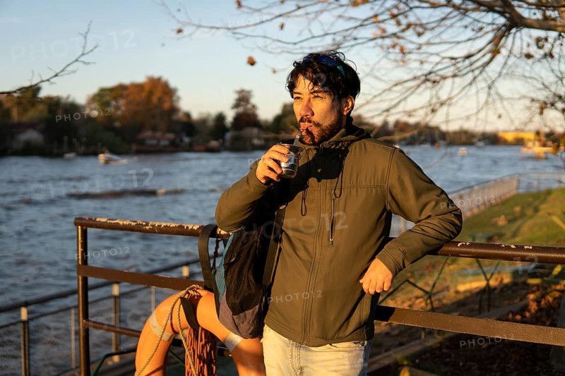 Latin man enjoying the sunset at the river while drinking mate