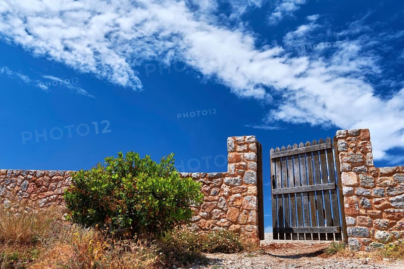 Countryside landscape. Rustic stone wall fence and aged black timber wicket door. Great blue sky with awesome clouds. Concept of opening opportunities