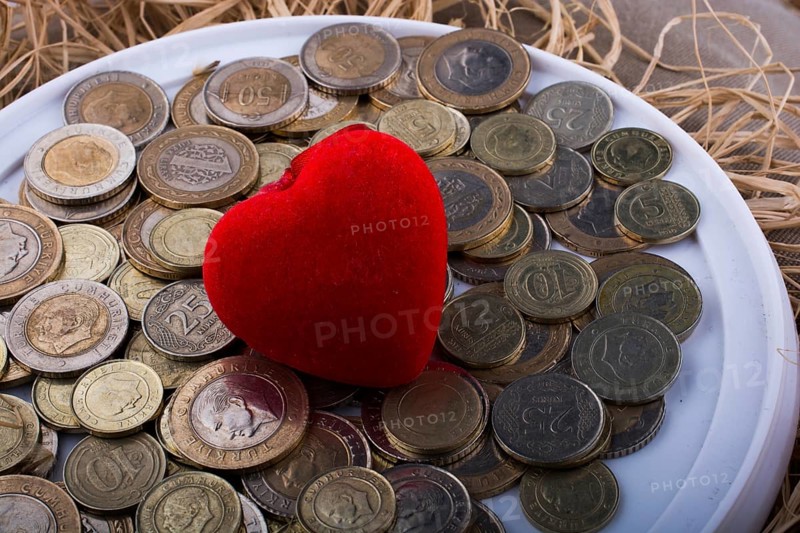Turkish Lira coins by the side of a red color heart shaped object on white background