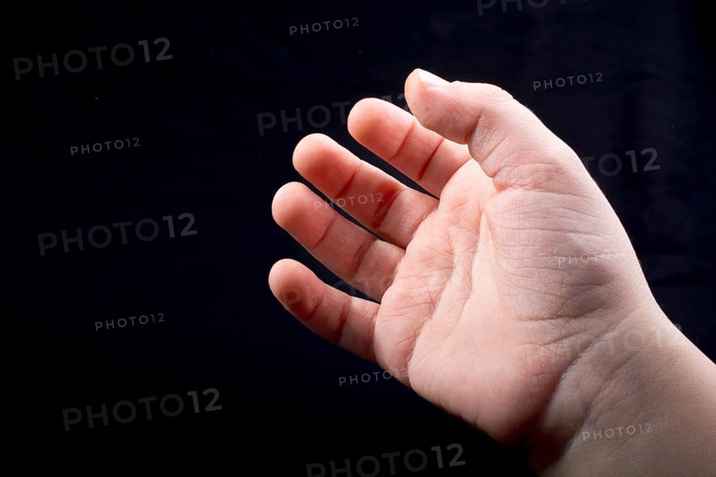 Five fingers of a child hand partly seen in black background