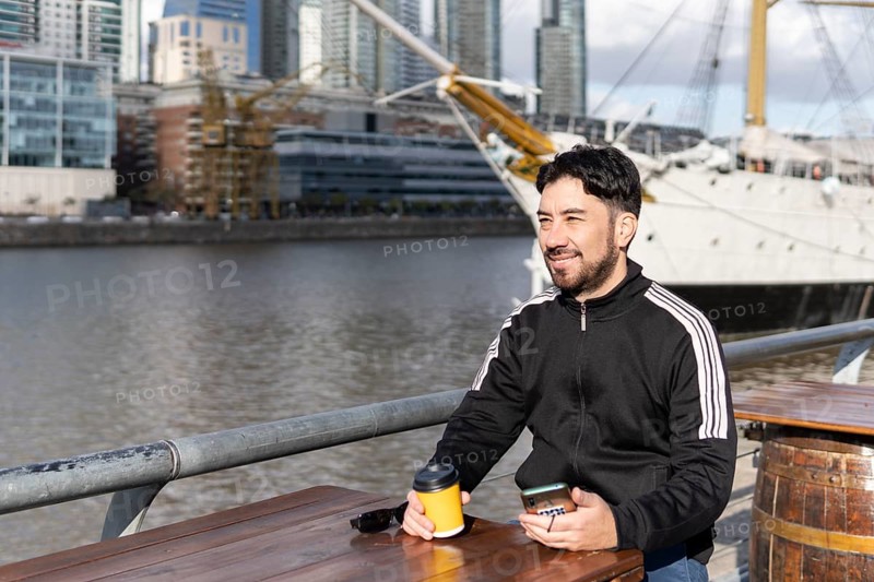 Latin tourist drinking coffee at an outdoor bar in Puerto Madero
