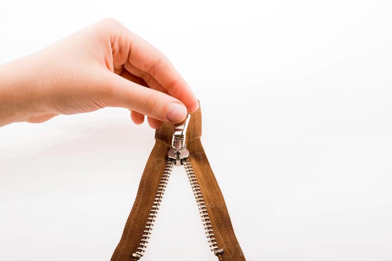 Hand holding color zipper on a white background