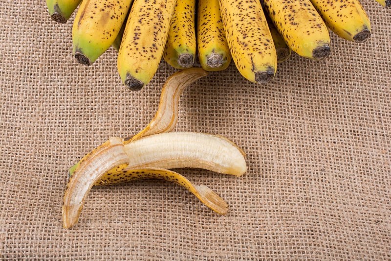 Bunch of yellow freckled bananas on a canvas texture