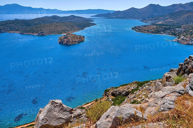 Aerial view of clear sea waters of harbor between Spinalonga island and peninsula