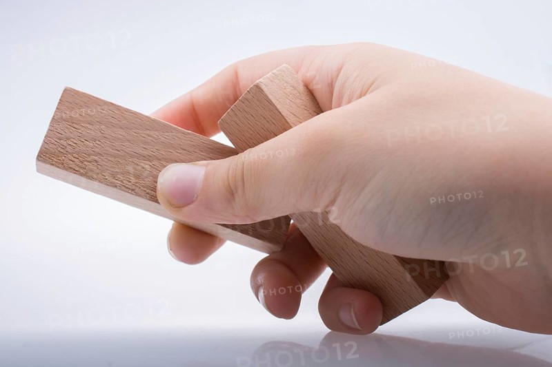 Hand holding wooden domino on a white background