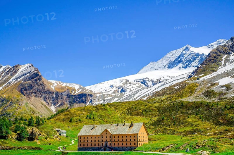 Big Building with Snow-capped Mountain and Blue Sky in Simplon Pass in Summer in Valais