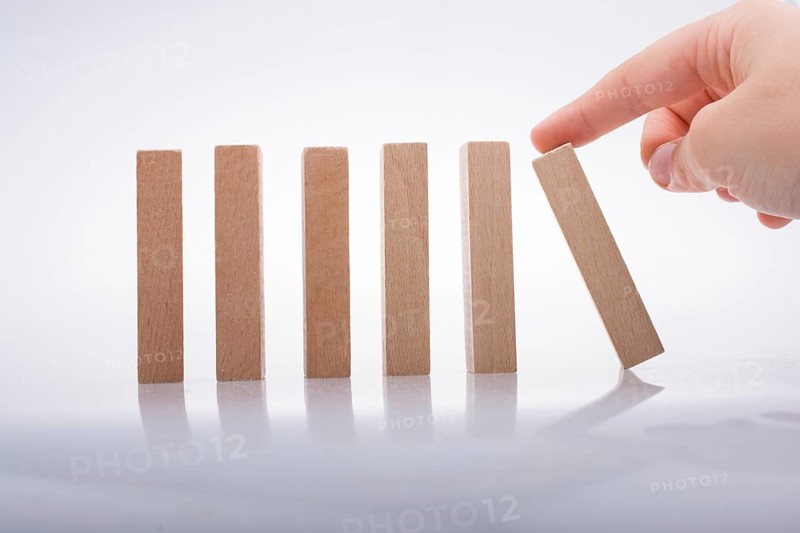 Hand holding wooden domino on a white background