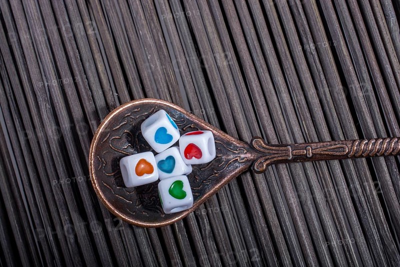 Colorful love cubes in a spoon on a straw mat