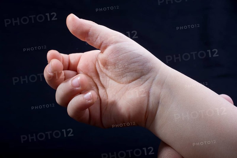 Five fingers of a child hand partly seen in black background