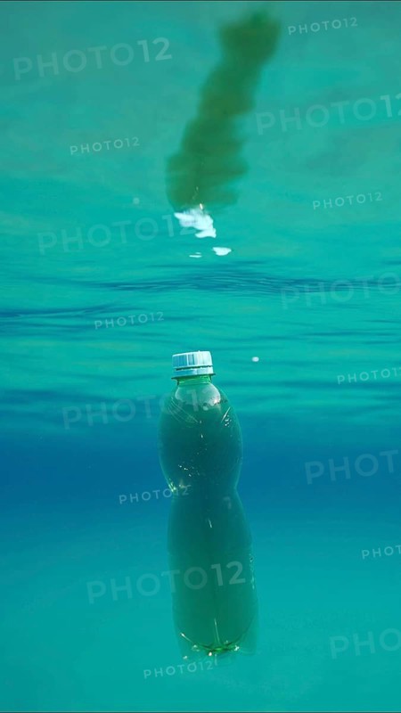 Green plastic bottle drifting under surface of blue water. Plastic pollution of Ocean