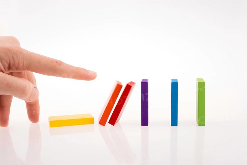 Hand playing with colored domino on white background