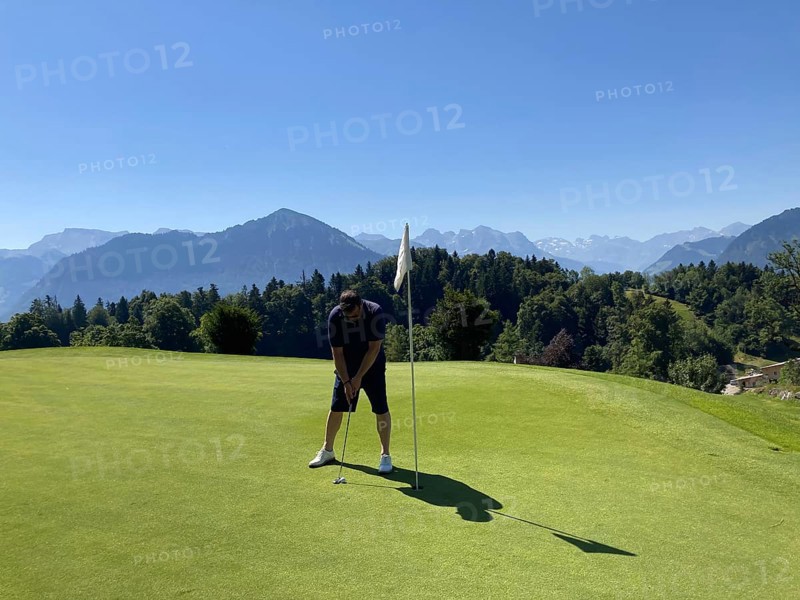 Golfer on Putting Green with Mountain View in a Sunny Summer Day in Burgenstock