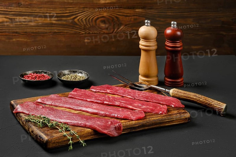 Raw beef strips on wooden cutting board
