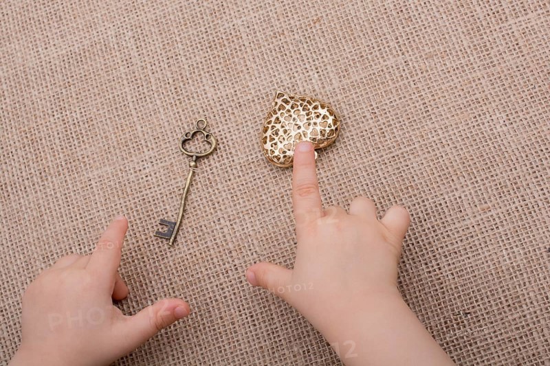 Heart shaped gold color metal object in hand