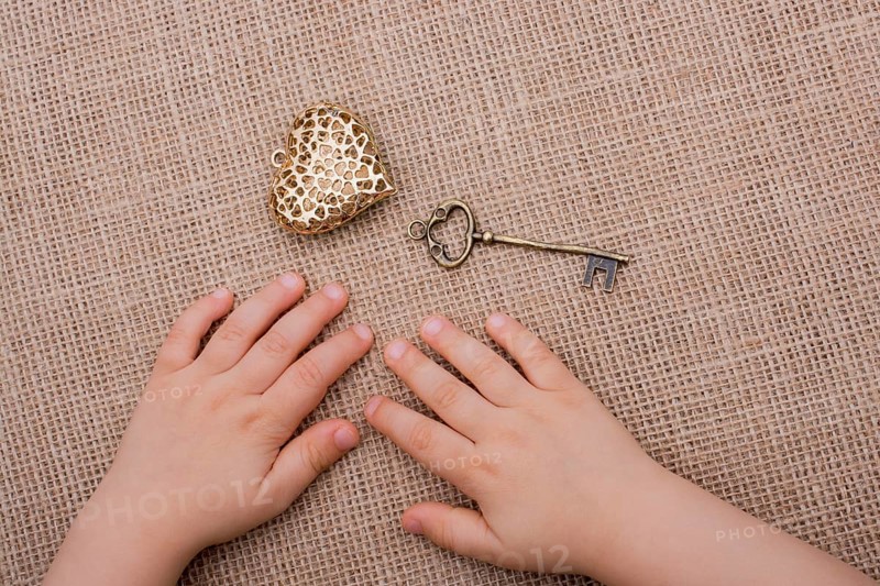 Heart shaped gold color metal object beside a hand