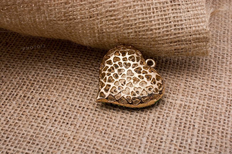 Heart shaped gold color metal object on canvas