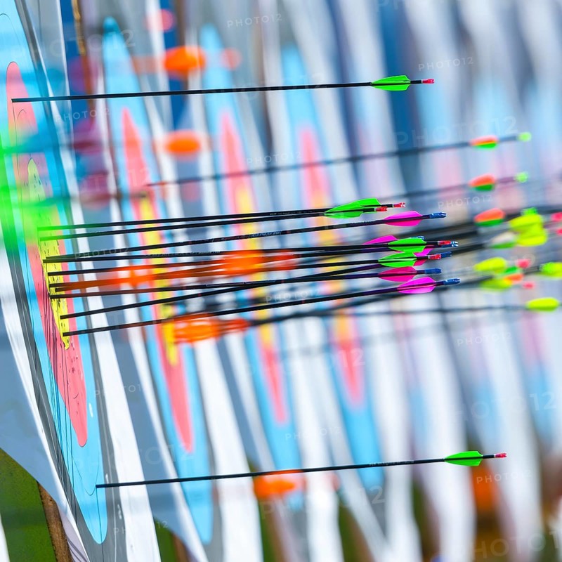 Lots of colourful arrows stuck in targets in archery