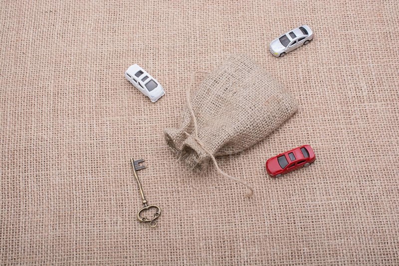 Key and toy cars around a sack on a linen canvas