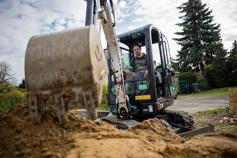 A construction worker sits in a mini-excavator at a building site. Berlin
