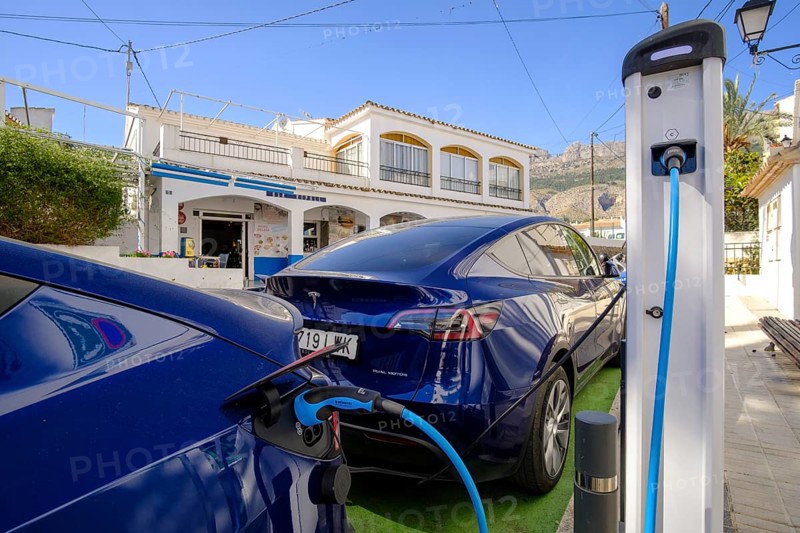 Two Tesla electric vehicles charging at a charging station in the village of Altea La Vella