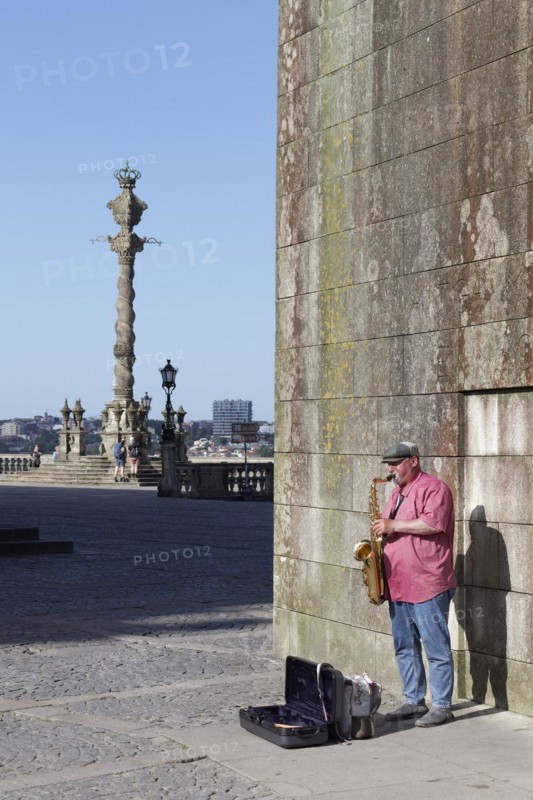 Street musician playing saxophones in front of the Se do Porto Cathedral