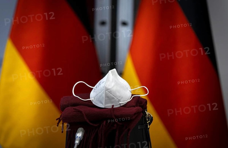 An FFP2 mask lies in front of Germany flags at the Federal Foreign Office. Berlin. 09.12.2020