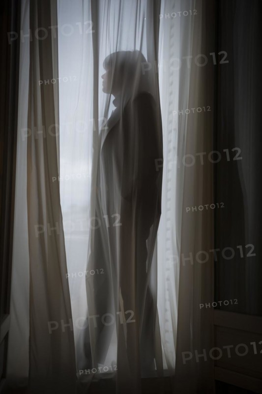Woman standing behind a curtain