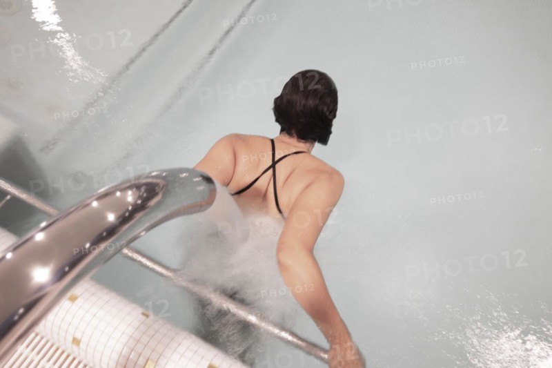 Woman Relaxing in a Hydro Massage Pool with Falling Water on Her Spine in Switzerland