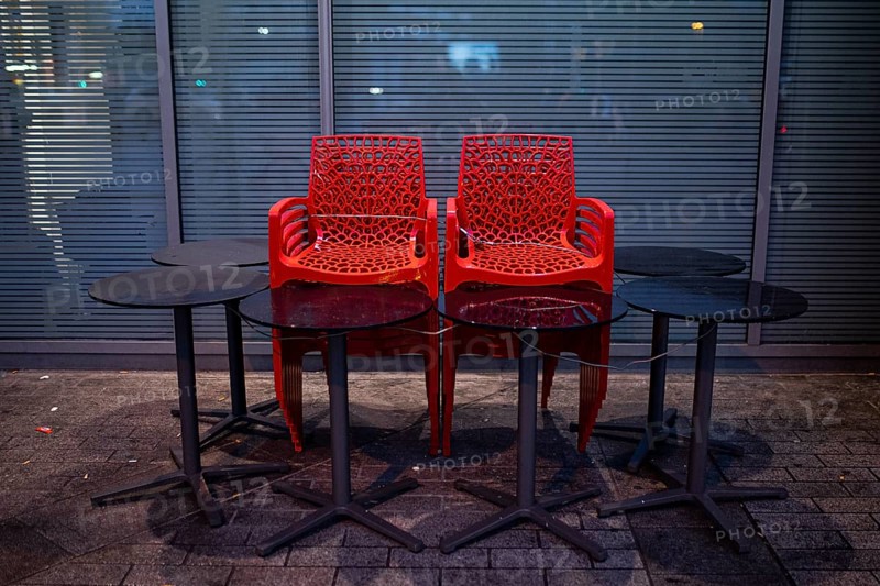 Assembled chairs and tables stand out in front of a closed cafe in Berlin