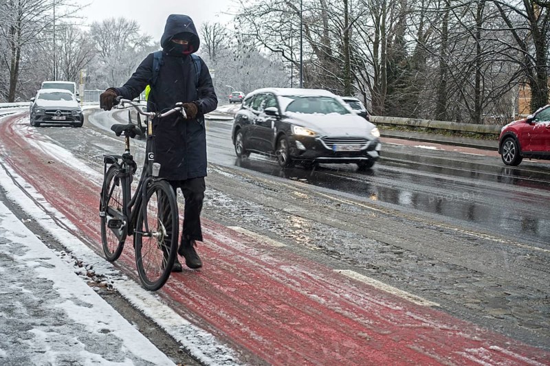 Cyclist walking on foot holding bicycle on slippery bike path