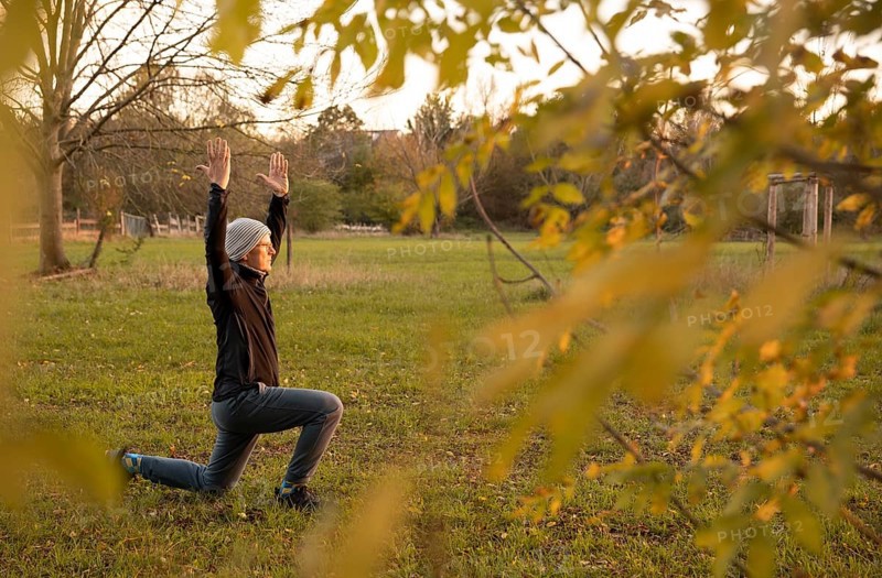Man stretching in a meadow in autumn. Yoga outdoors.