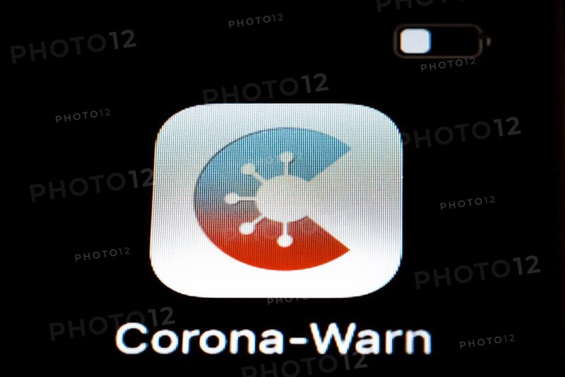 The Corona warning app is displayed on the screen of a smartphone. The app is designed to help trace and interrupt chains of infection of SARS-CoV-2
