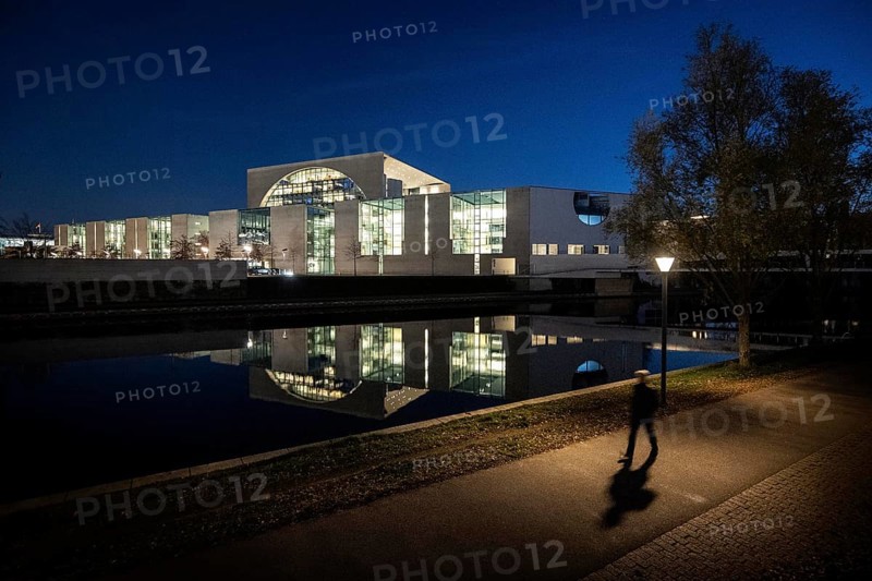 A person stands out in front of the Federal Chancellery at blue hour