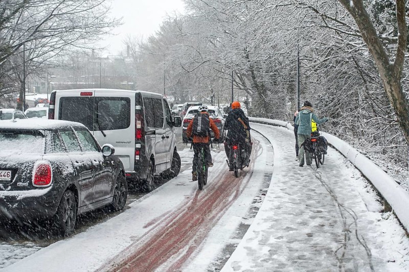 Cyclists walking on foot holding bicycles on slippery pavement