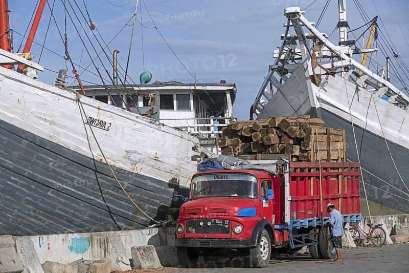 Truck loaded with timber in front of wooden pinisis
