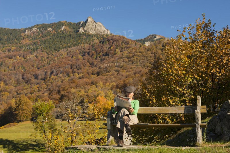 Woman sitting on a bench and reading newspaper