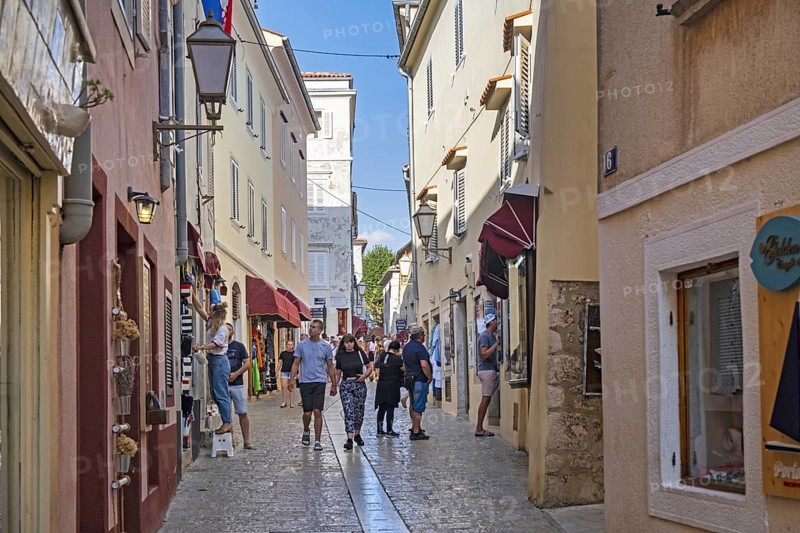 Tourists walking in alley with shops in the historic Old Town of Krk