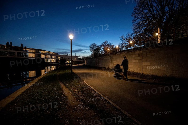 A woman with a pram stands out on the Spreebogen at blue hour